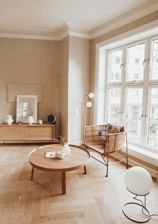 zeitlose Farben einfach eingerichtetes Wohnzimmer Weiß Beige und viel Holz Parkettboden geflochtener Sessel runder niedriger Holztisch
