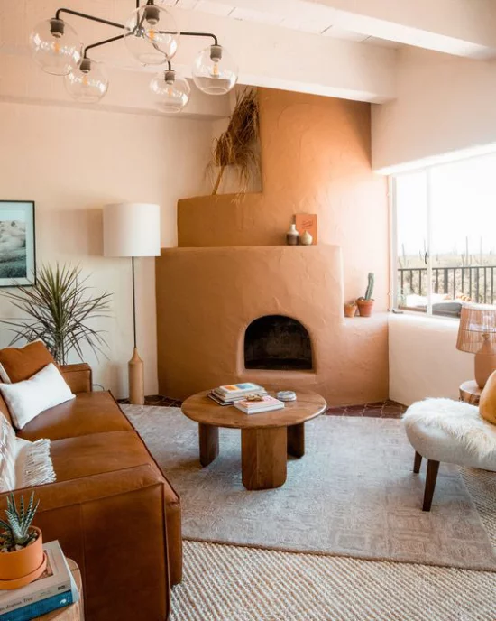 zeitlose Farben warmes einladendes Wohnzimmer Blickfang Kaminofen in gebrannter Siena Ledersofa links runder Holztisch