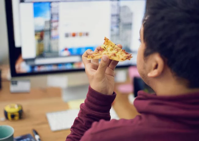 Diätfallen Pizza essen vor dem PC bei der Arbeit schlechte Gewohnheit im Home Office