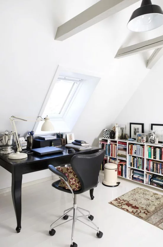 Heimbüro auf dem Dachboden weißes Ambiente schwarze Büromöbel niedriges Bücherregal an der Wand