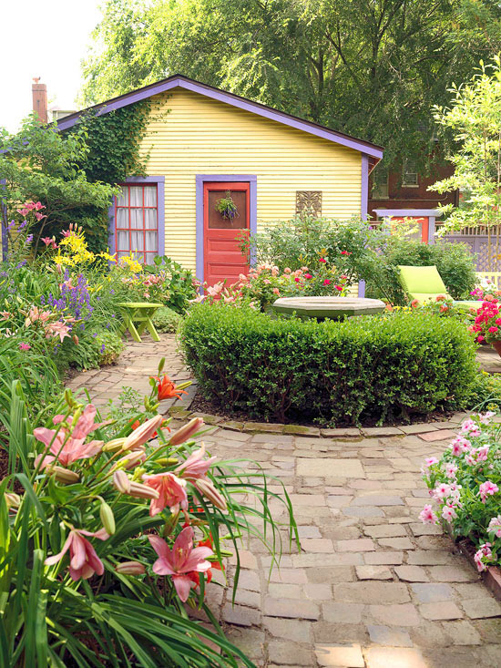 mehr Farbe in den Garten bringen rosa Lilien und Pelargonien am Rande des Blumenbeetes schöner Blick in einen Bauerngarten