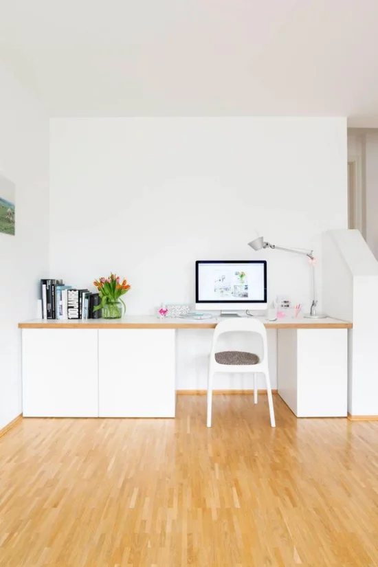 zeitgenössisches Home Office Holzboden weiße Büromöbel sauberes Ambiente Bücher daneben Vase mit Tulpen
