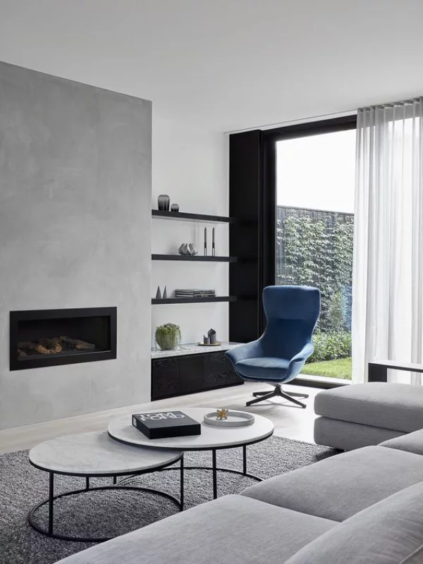 modernes Wohnzimmer Grau als Grundfarbe kleine schwarze Akzente ein Designklassiker blauer Sessel als Blickfang