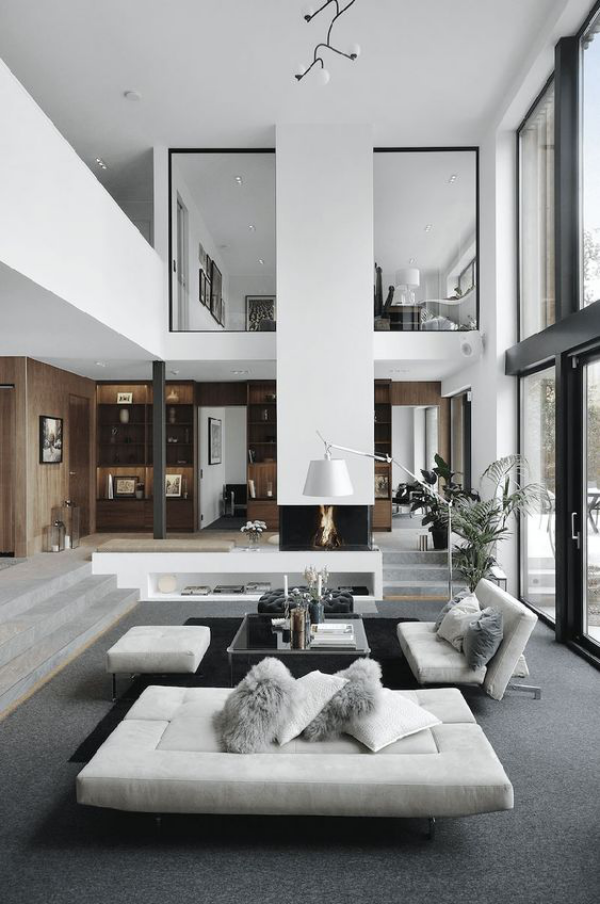 modernes Wohnzimmer auf zwei Ebenen schickes Interieur weiße Möbel grauer Bodenbelag Bogenlampe Wurfkissen auf den Sofas