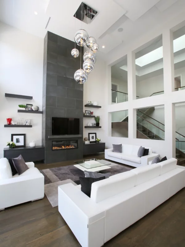 modernes Wohnzimmer weiße Möbel graue Akzentwand ausgefallene Hängeleuchten Glastisch grauer Teppich