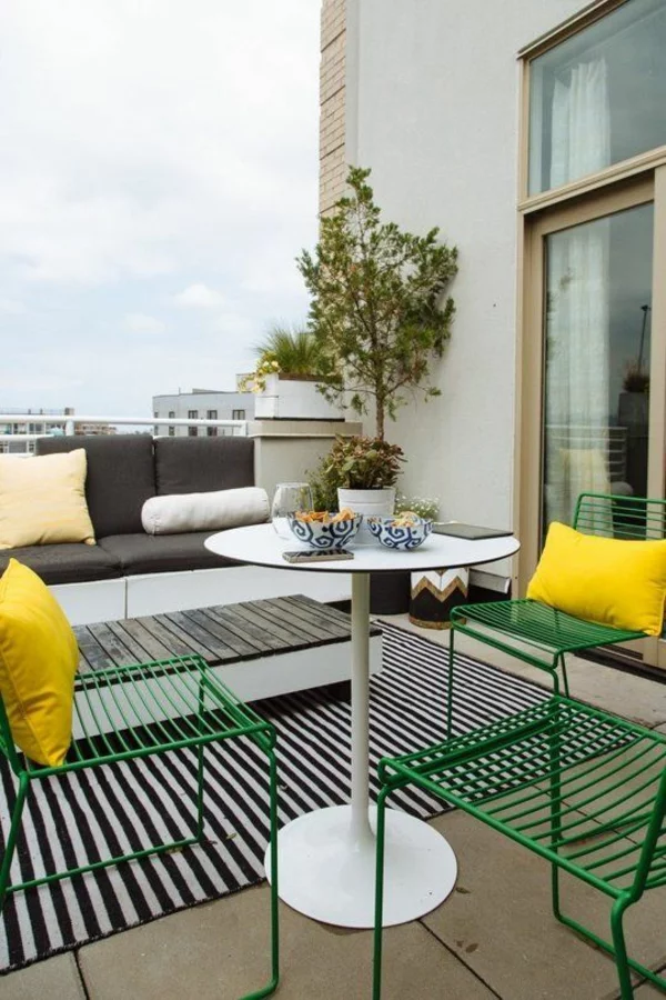 Terrasse dekorieren mit gelben Dekokissen und Streifenteppich in Weiß und Schwarz