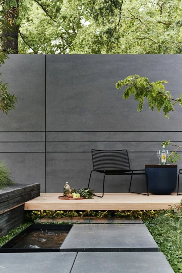 Terrassentrennwand aus Beton und schwarze Außenmöbel
