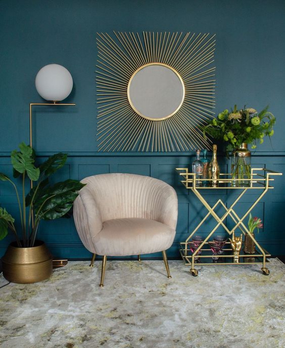 Goldene Akzente im Interieur Wohnzimmer Sessel Getränkeanrichte dunkle Wandfarbe runder Wandspiegel wie Sonne goldene Strahlen