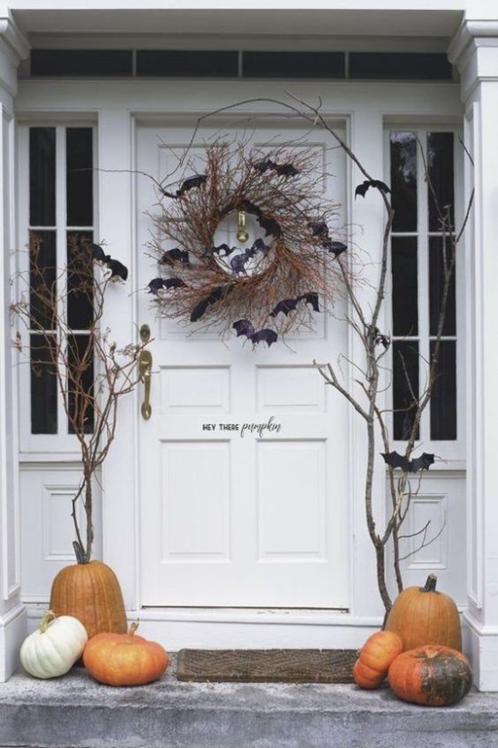 Halloween Kränze Deko an der Haustür Kranz aus trockenen Ästen schwarze Fledermäuse Kürbisse beiderseits der Tür