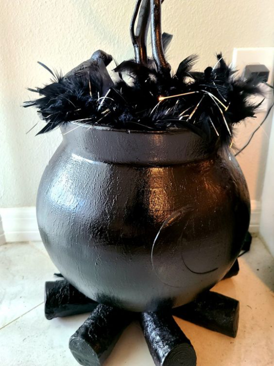 Hexenkessel moderne Halloween Deko aus Künstlichen Materialien schwarzer Kessel schwarzes Brennholz schwarze Federn Raben