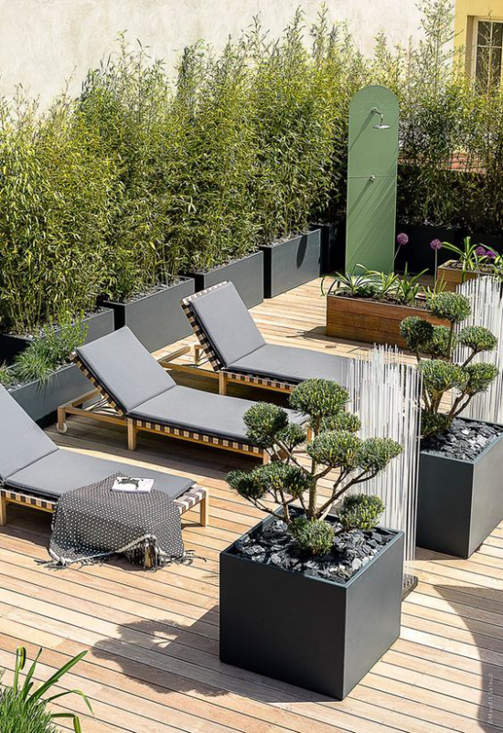 minimalistische Terrassengestaltung Dachterrasse Ruheort geflochtene Liegestühle große Pflanzkübel viel Grün