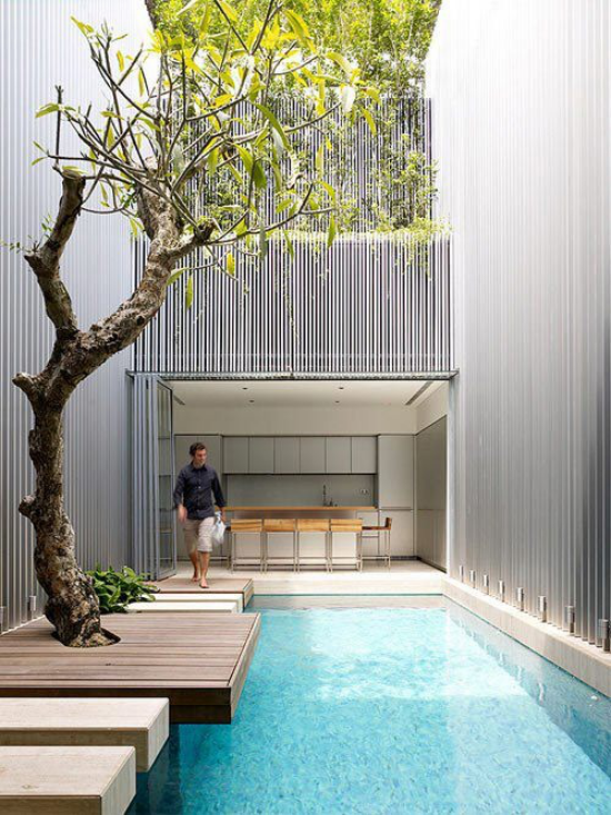 minimalistische Terrassengestaltung Pool junger Mann daneben kleine Terrasse zwischen Häuser im minimalistischen Stil keine Möbel nichts Überflüssiges