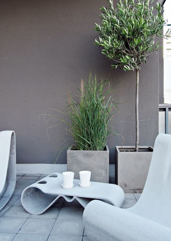 minimalistische Terrassengestaltung ausgefallene minimalistische Möbel zwei Betonkübel grüne Pflanzen Grau dominiert
