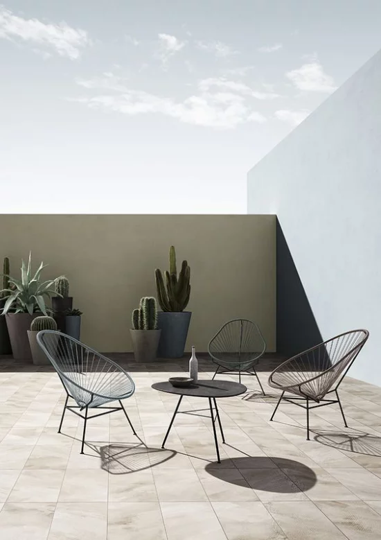 minimalistische Terrassengestaltung einfaches Gestaltungskonzept runder Tisch Stühle aus Metall Betonkübel mit Sukkulenten