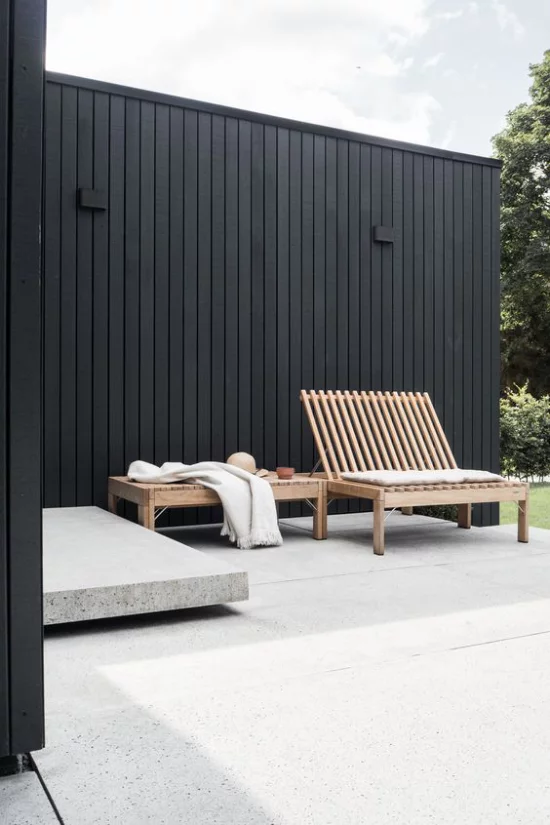 minimalistische Terrassengestaltung einfaches Gestaltungskonzept schwarze Wand Betonboden Holzbank nichts Überflüssiges