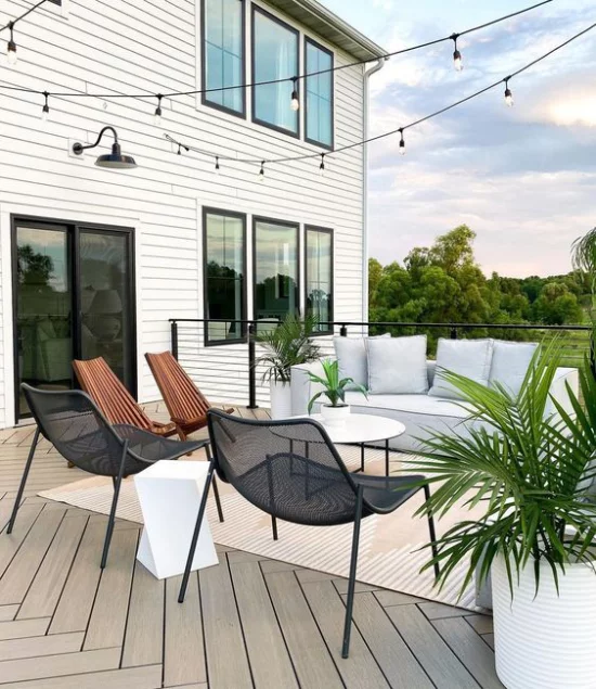 reduzierte Terrasseneinrichtung runder Tisch Metallstühle hellgraue Outdoor-Couch