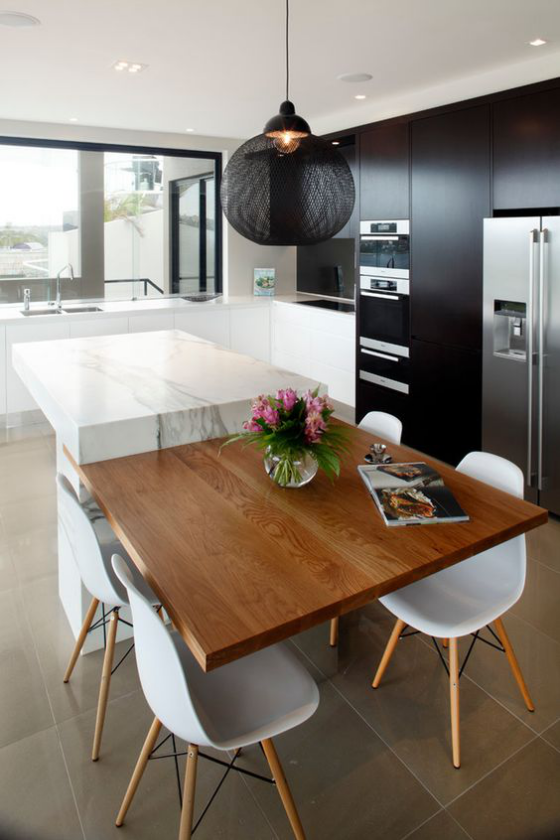 moderne Küche extravagantes Küchendesign schwarze grifflose schränke eingebaute Geräte weiße Kücheninsel Holzplatte weiße Stühle schwarze Hängelampe