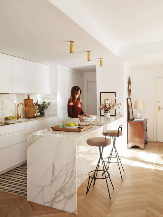moderne Küche sehr elegantes Design große Kücheninsel aus weißem Marmor junge Frau beim Speisenzubereitung