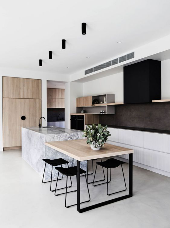 moderne Küche weiße Kücheninsel aus Marmor gepaart mit hellem Holz Tisch Schränke schwarze Hocker schwarze Deckenstrahler