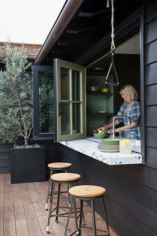 Faltfenster moderne Fensterkonstruktion geöffnet direkten Kontakt leichter Übergang zum Outdoor-Bereich Frau beim Kochen in der Küche