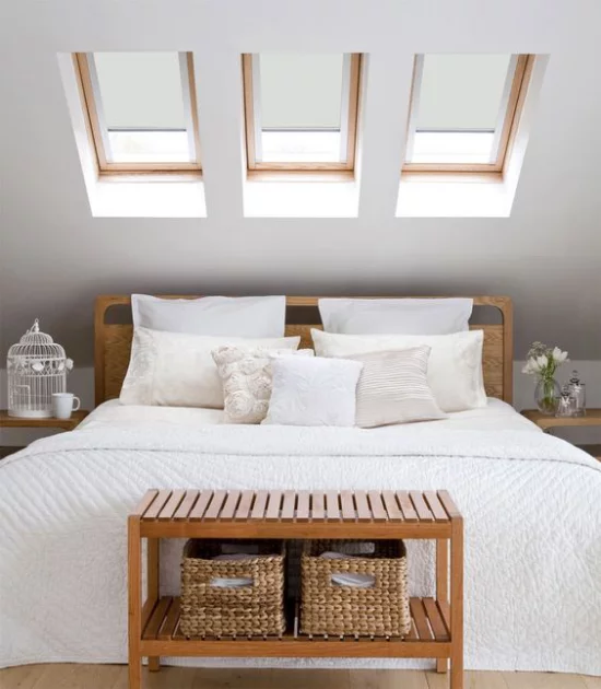 Moderne Dachfenster im Schlafzimmer über dem Schlafbett romantische Raumgestaltung weiter Bett weiße Bettdecke Kissen helles Holz