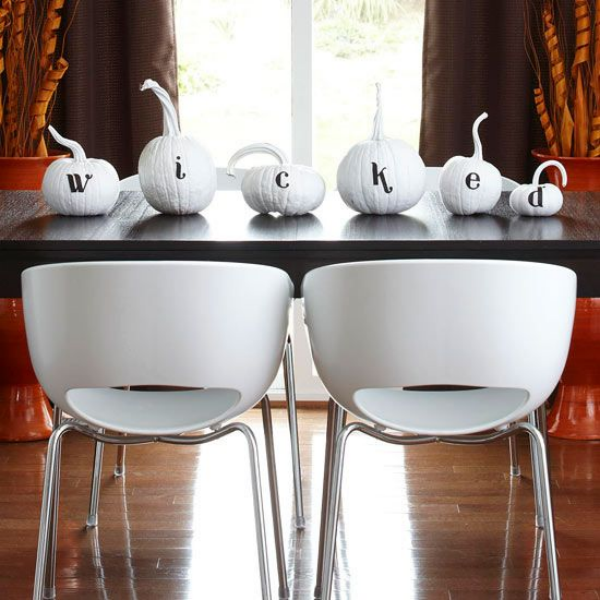 Weiße Halloween Deko Ideen weiße Kürbisse auf einem schwarzen Esstisch geschnitzt beschrieben Angst verbreiten