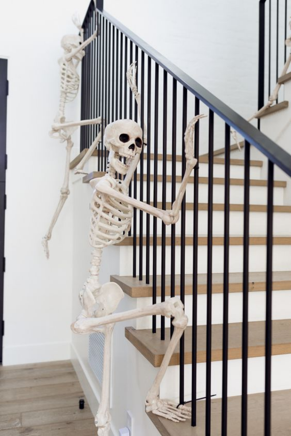 Weiße Halloween Deko Ideen zwei weiße Skelette am Treppengeländer Angst und Schrecken vertreiben