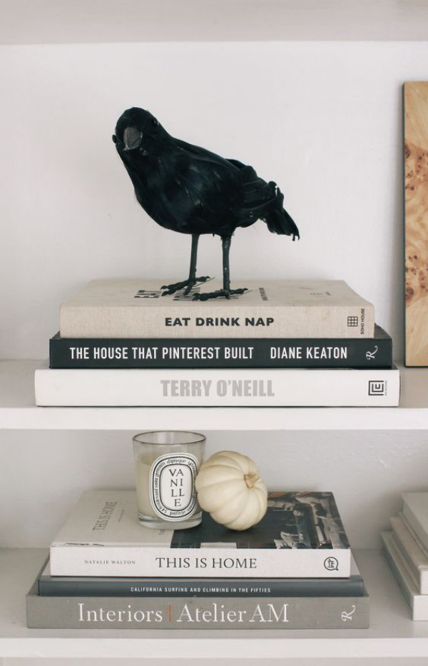 minimalistische Halloween Deko Bücher ein schwarzer Rabe darauf Symbol für Weisheit