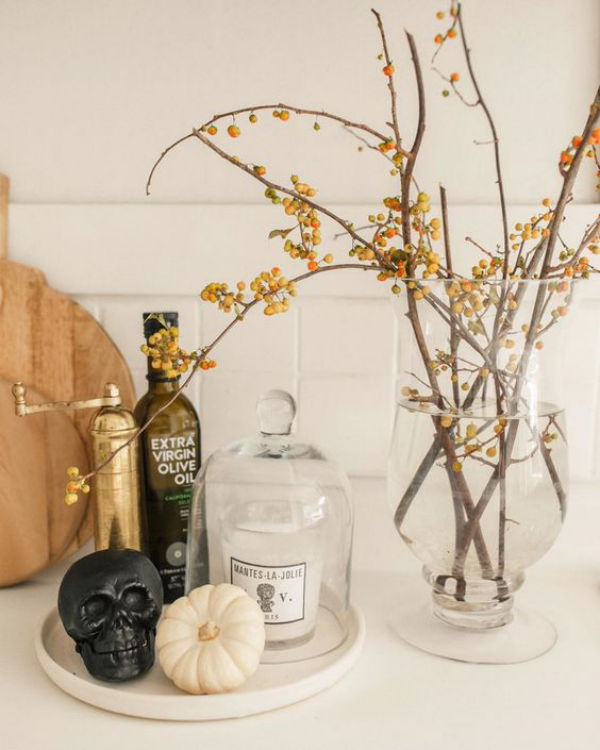 minimalistische Halloween Deko weißer Kürbis schwarzer Totenkopf Flaschen Vase mit Zweigen