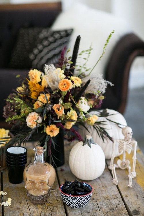 natürliche Halloween Deko auf dem ungedeckten Tisch Totenköpfe Skelett vase mit Blumen Kürbisse