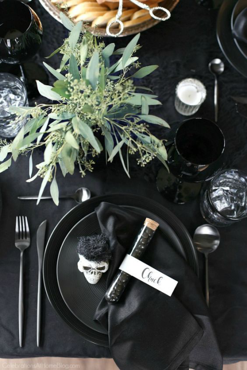 natürliche Halloween Deko festlich gedeckter Tisch in Schwarz Tischdecke Geschirr Besteck Grünzeug in Vase in der Mitte