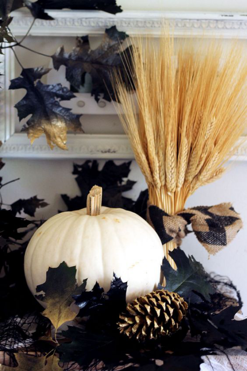 natürliche Halloween Deko stilvoll arrangiert weißer Kürbis schwarze Herbstblätter Weizenstängel