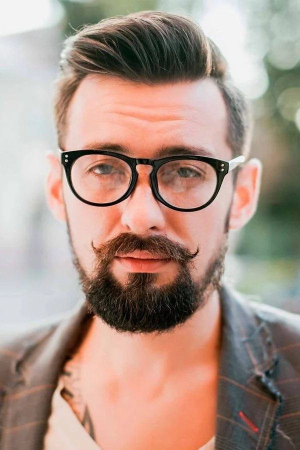 aktuelle Bartfrisuren neue Trends Bart und Schnurrbart junger Mann mit Brille gut gestylter Bart 
