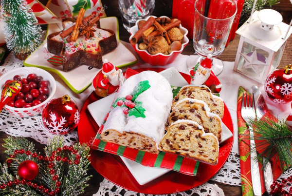 Christstollen beliebtes Gebäck in der Weihnachtszeit festlich gedeckter und dekorierter Tisch dominierende Farben Rot Grün Weiß Kugeln Laterne Tannengrün