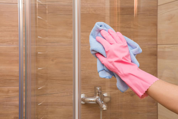 Dusche reinigen Frau rosa Schutzhandschuhe die Duschwand trocknen weiches blaues Tuch