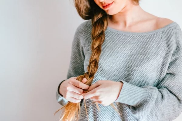 Haare schneller wachsen lassen Tipps und Hausmittel junge Frau bindet einen Zopf gesundes Haar 