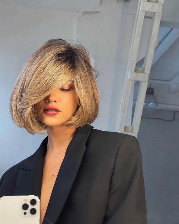 Italienischer Bob Trend-Frisur 2021-22 blondes Haar bis Kinnlinie stark zur Seite geföhnt