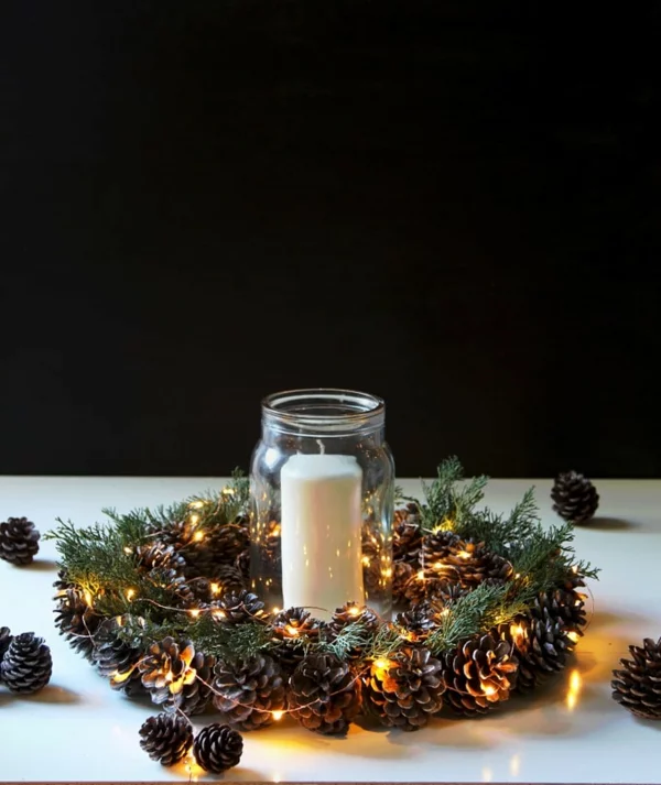 Weihnachtsgesteck mit Teelicht, Zapfen und Lichterkette