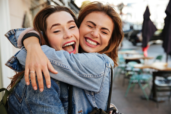 Close-up photo of laughing woman friends hugging each other on c