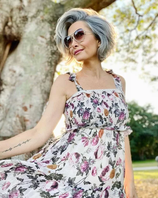 Frisuren für graue Haare ab 60 Long Bob mutig trendy feminin Dame mit Sonnenbrille florales Muster auf dem Sommerkleid