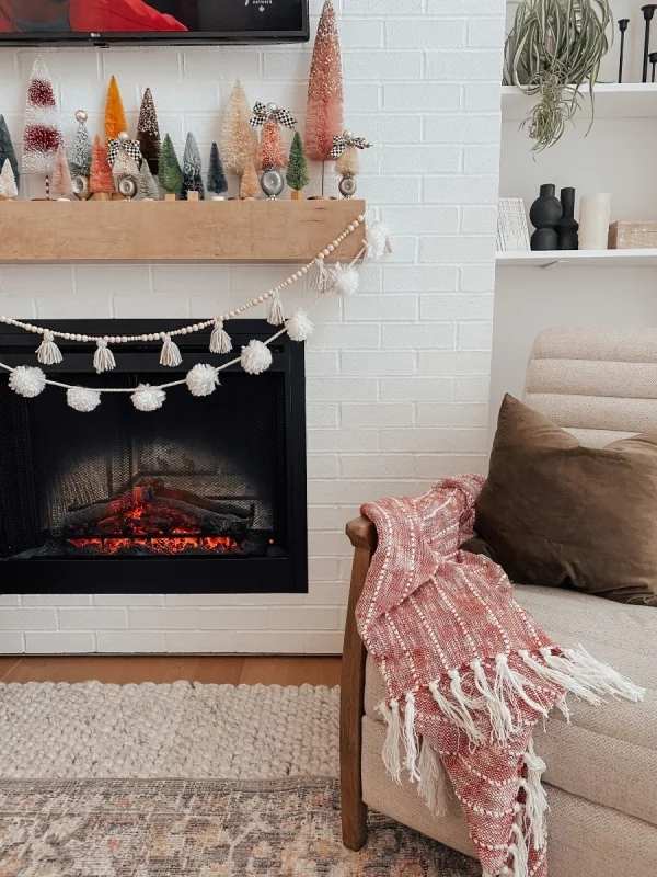 Winterdeko im Wohnzimmer Gemütlichkeit pur dekorierter Kamin loderndes Feuer Sessel Kuschelecke weiches Kissen