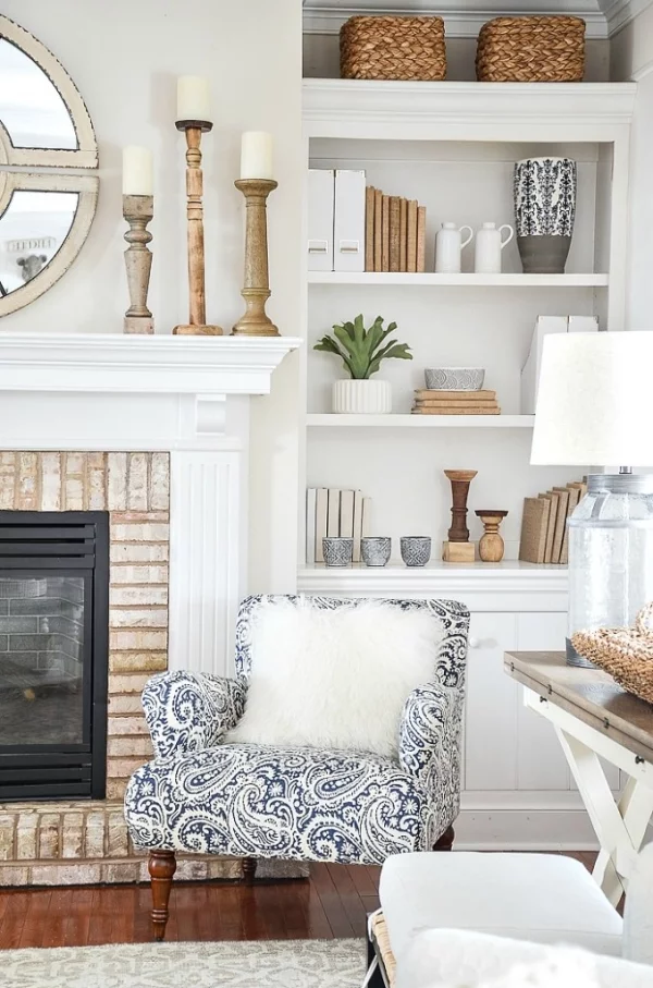 Winterdeko im Wohnzimmer Sessel weißes Kunstpelzkissen Bücherwand gemütliche Ecke