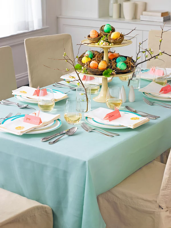 Osterdeko für Kinder Tischdecke in Pastellgrün Tortenständer in der Mitte mit Nestern bunte Eier blühende Zweige