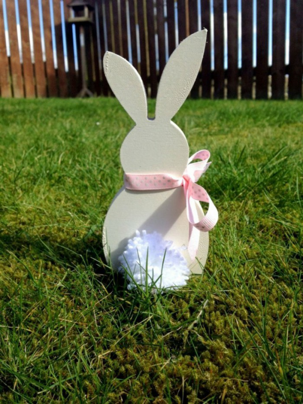 Osterdeko für draußen DIY Ideen eine Hasenfigur leicht gemacht mit rosa Schleife weiße Blume im Gras