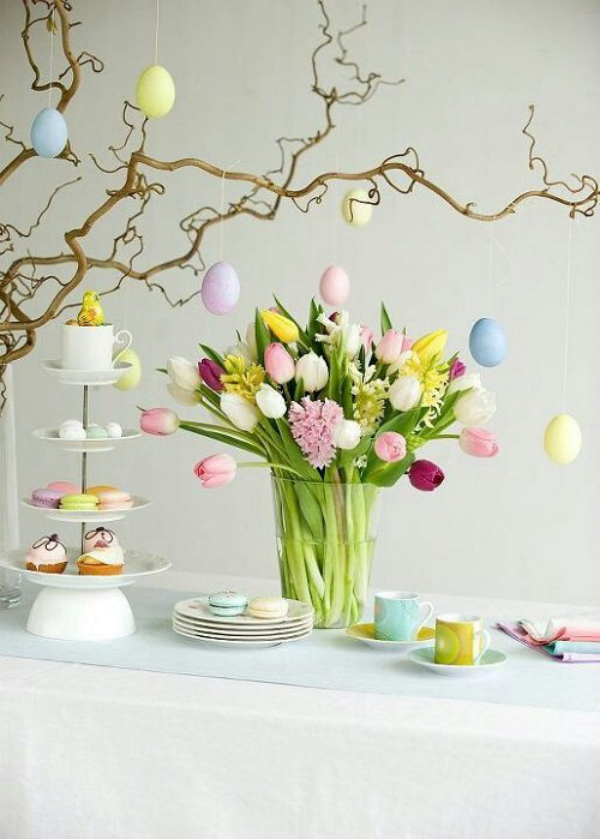Osterdeko für draußen festlich gedeckter Tisch Vase mit Tulpen Zweige mit bunten Eiern dekoriert