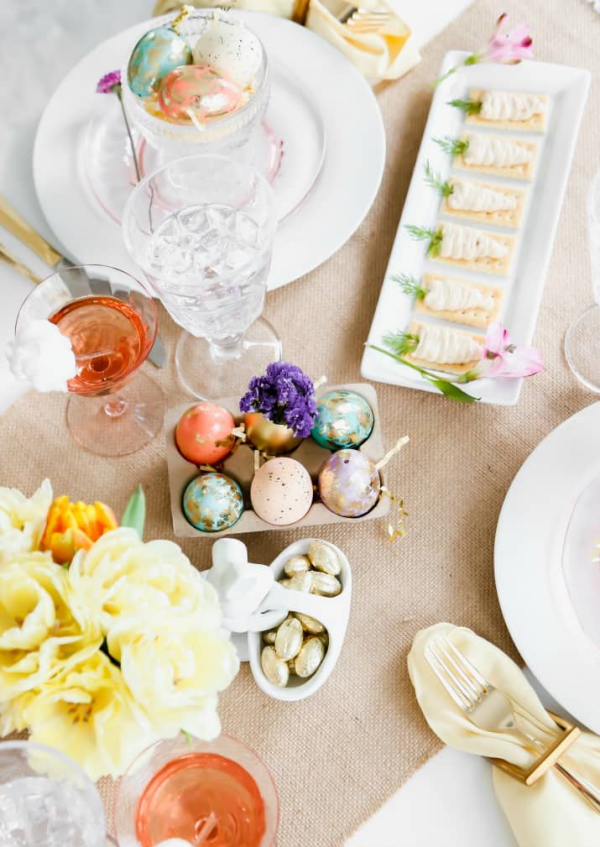Ostertafel dekorieren beigefarbene Tischdecke Eier Gläser hellgelbe Blumen schönes Geschirr