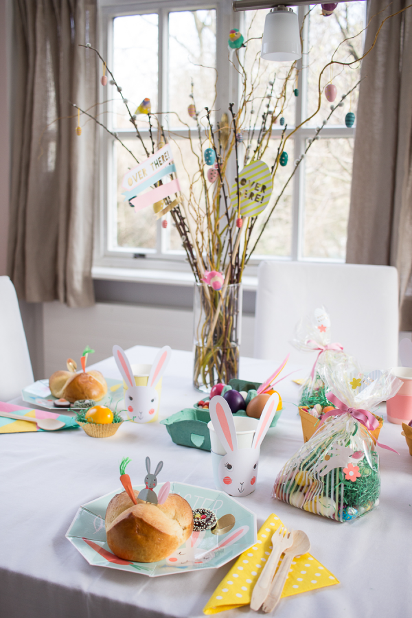 Tischdeko zu Ostern Frühstückstisch am Ostermorgen Vase mit geschmückten blühenden Zweigen Plastikbecher in Hasenform bunte Eier