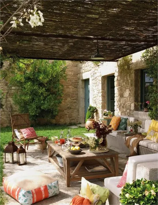 mediterraner Außenbereich Sitzecke überdachte Terrasse viel Grün Holztisch bequeme Sitzmöbel Laternen
