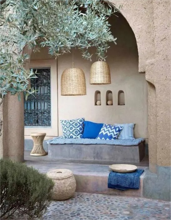 mediterraner Außenbereich raue Materialien Betonwände Sitzbank minimalistisch blaue Sitzkissen