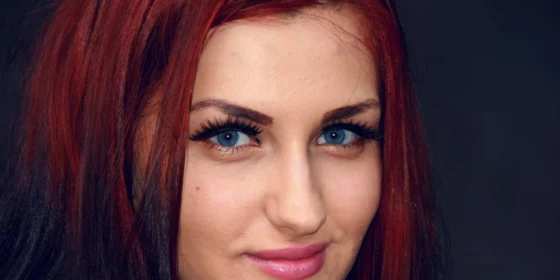 Frauengesicht mit blauen Augen und dunkelroten Haaren 